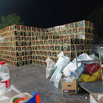 Large stacks of black retail cartons staged at night for wholesale dried fruit shipping